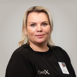 Nærbillede af en kvindelig medarbejder i Cerix-uniform med navneskilt; blondt hår, gyldne øreringe, let smil og velplejet ansigt. Billedet præsenterer Cerix som klinik og viser fokus på ansigtsbehandlinger, fx Botox. Professionelt, venligt og naturligt portræt med neutral baggrund, hoved- og skuldervisning.