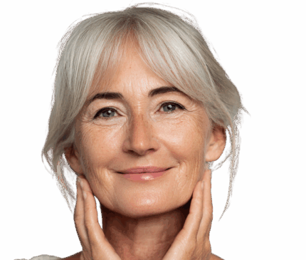 Nærbillede af en smilende, moden kvinde med gråt hår, der blidt rører sine kinder med begge hænder. Billedet illustrerer ansigtsbehandlinger hos Cerix, såsom Botox, fillers eller skinbooster, der hjælper med at forynge og opfriske huden i ansigtet.