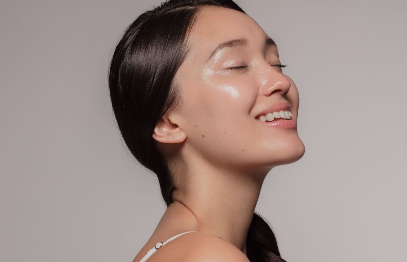 Portræt af en kvinde med sund, glødende hud i profil, smilende med lukkede øjne. Cerix viser resultatet af ansigtsbehandling (Botox) med fokus på ansigt og hals. Neutral baggrund fremhæver glat hud og naturligt, afslappet udtryk og fremhæver klinisk præcision og naturlige resultater.
