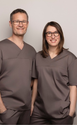 Portræt af to smilende sundhedsfaglige medarbejdere fra Cerix, iført brune klinikuniformer og stående side om side foran en neutral baggrund. Billedet viser deres ansigter og overkroppe og repræsenterer Cerix’ professionelle tilgang til kosmetiske behandlinger, herunder ansigtsbehandlinger som Botox, uden at en konkret behandling udføres.