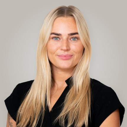 Portræt af en smilende blond kvinde med langt, glat hår, blå øjne og sort bluse foran en neutral baggrund. Billedet viser ansigtet og håret og kan illustrere Cerix som virksomhed inden for kosmetiske behandlinger, herunder ansigtsbehandlinger, Botox og hårrelaterede behandlinger.